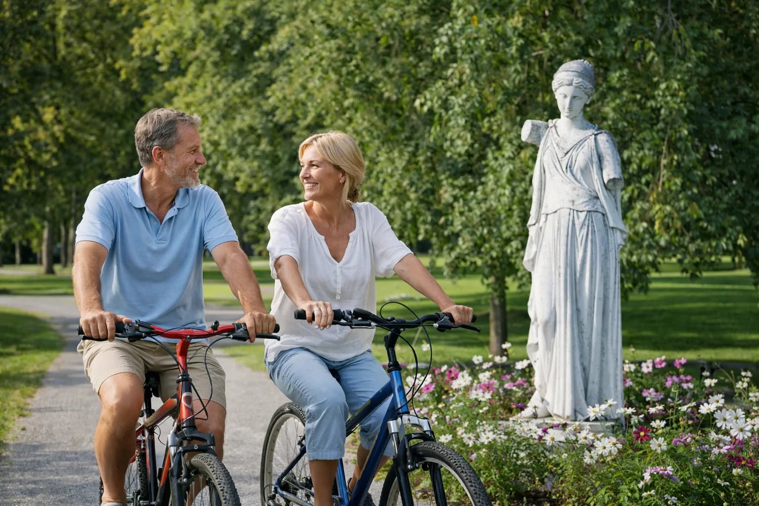 Couple cycling through a park past a statue of the Greek goddess Hebe